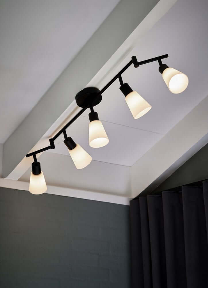 Deckenstrahler Cole 5-Spot mit fünf schwenkbaren Lampenschirmen an einer Decke montiert.