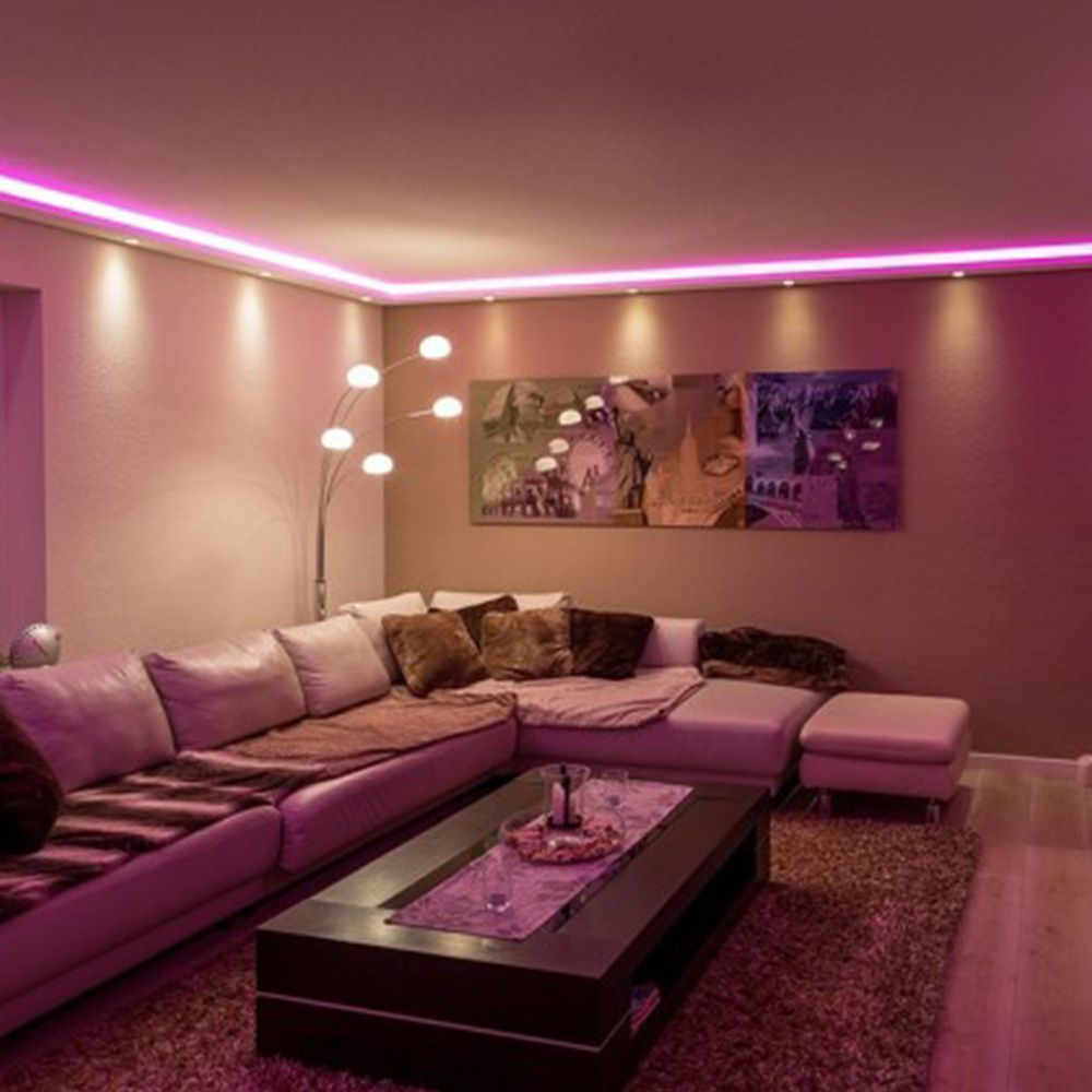 Modernes Wohnzimmer mit indirekter Beleuchtung in Pink und stilvoller Stuckleiste an Wand und Decke.