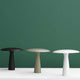 Design Tischlampe Shelter Ø 41cm Schwarz, grün und weiß auf einem Tisch vor grünem Hintergrund.