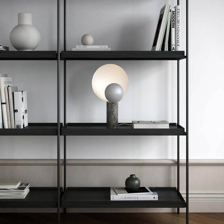 Caché table lamp marble on a modern shelf with decorative objects and books.