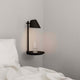 LED Wandleuchte Stay mit USB Schwarz an einer Wand neben einem Bett mit Glas auf dem Ablagebrett.