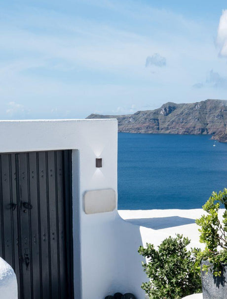Dewei LED Außenwandleuchte 3000K IP54 an weißer Wand am Hauseingang mit Blick aufs Meer