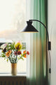 Dial Wandleuchte neben einem Blumenvase mit bunten Blumen am Fenster.