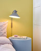 Dial Wandleuchte in modernem skandinavischem Design neben einem Bett auf einem runden Nachttisch.