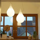 Zwei schwerelose Pendelleuchten in Tropfenform bei Fenster, warmes Licht und ästhetisches Design betonen den Raum.