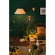 Stimmungsvolle Wohnlandschaft mit verschiedenen Lampen und Pflanzen auf grünem Hintergrund.