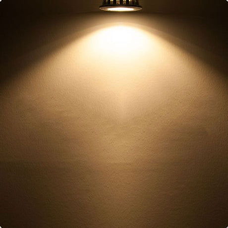GU10 ES111 HighPower LED Leuchtmittel 75° 1050lm 2700K strahlt warmes Licht auf eine Wand.