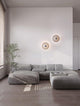 Edem LED Wandleuchte Ø 25cm 3000K an einer modernen Wand mit grauem Sofa und Pflanzen im Raum.