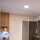 Ultraflaches dimmbares LED-Panel Ø 23cm in modernem Badezimmer über Dusche installiert.