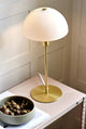 Ellen 20 Tischlampe auf einem Tisch mit dekorativem Geschirr, minimalistisches skandinavisches Design.
