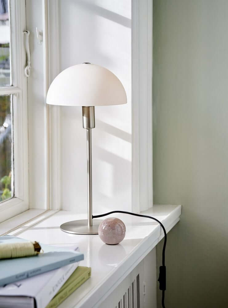 Ellen 20 Tischlampe auf einem Fenstersims mit minimalistischem skandinavischem Design.