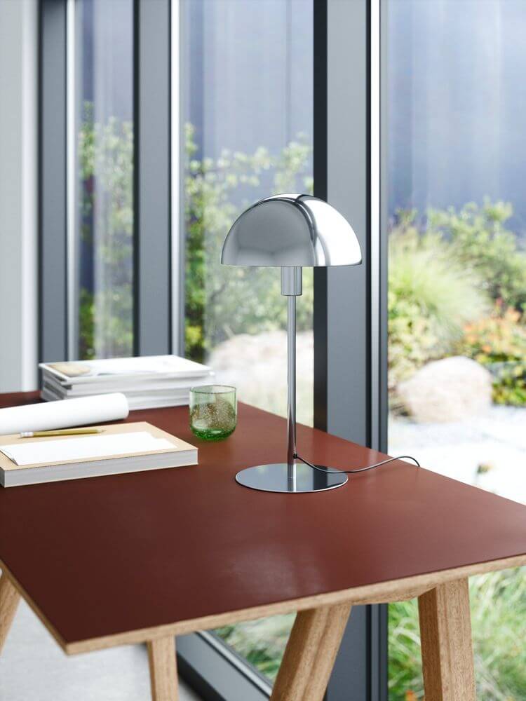 Ellen 20 Tischlampe auf einem Tisch mit rotem Tischblatt und Blick auf einen Garten.