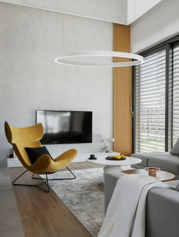 Elowen LED Pendelleuchte Ø 98cm 3000K Up & Down im modernen Wohnraum mit gelber Lounge-Sessel und Fernseher