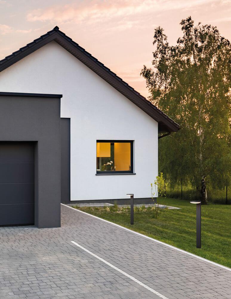 Enzi LED Außenwegeleuchte 3000K Dunkelgrau IP54 beleuchtet den Weg neben modernem Haus mit Garten.