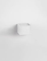 Weißer quaderförmiger Wandbehälter in minimalistischem Design an einer Wand montiert.
