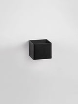 Schwarze, quaderförmige LED Wandleuchte, moderne und minimalistische Inneneinrichtung, indirekte Beleuchtung.
