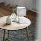 Adda Tischleuchte E14 Weiß auf einem Holz Tisch neben einer Vase und einem runden Teppich.