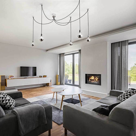 Moderne Blog Pendellampe Metall in einem stilvollen Wohnzimmer mit Sofa und Kamin.