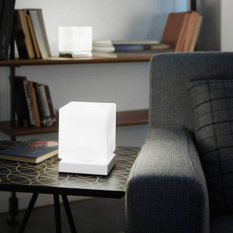Lampe de table Brenta LED en métal sur une table à côté d’un canapé et de livres en arrière-plan.