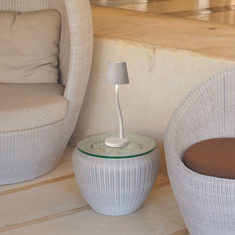 Judy LED Akku-Tischlampe mit Touch-Dimmer IP54 auf einem Tisch neben modernen Sesseln.
