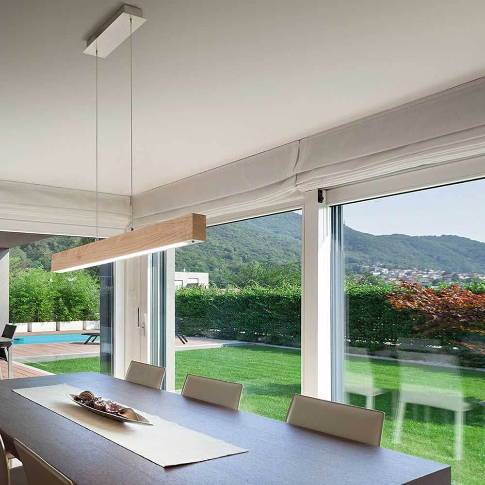 LED Pendellampe Badia aus Holz über einem eleganten Esstisch mit Blick ins Freie.