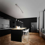 Moderne LED Pendelleuchte Delta aus Metall in stilvoller schwarzer Küche mit Holzdetails.