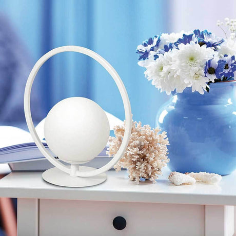 LED Tischlampe Sirio Rund auf einem Tisch mit Blumen und Dekoration.