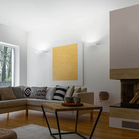 Gemütliches Wohnzimmer mit LED Wandlampe Emma 4300lm Weiß, goldener Wandkunst und modernem Mobiliar.