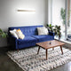 LED Wandleuchte Lotus Aluminium über einem blauen Sofa im modernen Wohnzimmer.