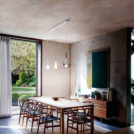 Lila Pendelleuchte aus Metall im modernen Esszimmer mit Holztisch und großen Fenstern.