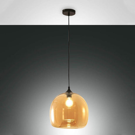 Maias elegante glas pendel i rav hænger elegant over et spisebord.