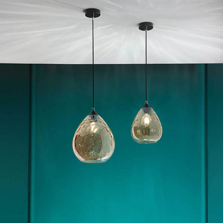 Pendellampe Gisella Bernsteinfarben, modern und elegant, mit bernsteinfarbenen Glaskörpern an einem grünen Hintergrund.