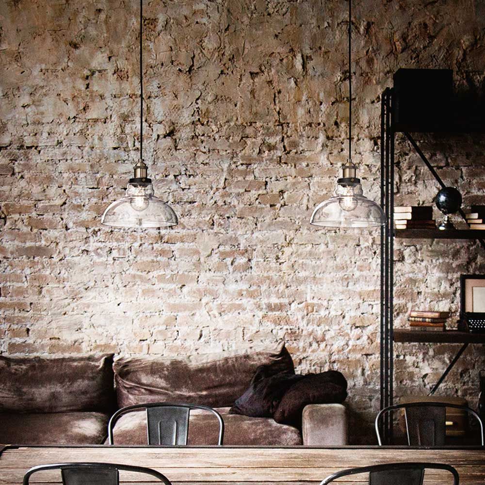 Pendelleuchte Olos Ø 25cm im modernen Wohnraum mit Ziegelwand und gemütlichem Sofa.