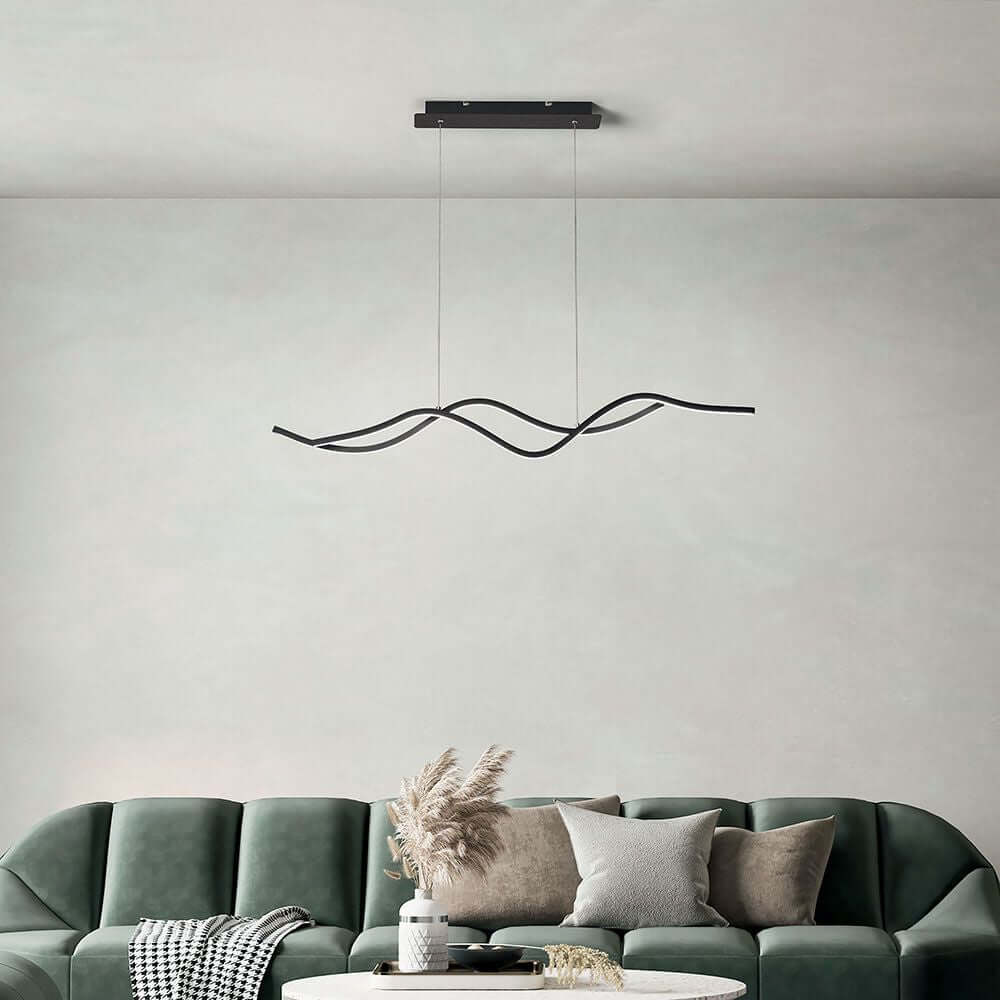 Sinuo LED Hängeleuchte Metall Gewellt in modernem Raum über grünem Sofa mit Kissen.