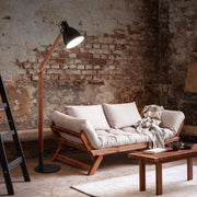 Klassische Leseleuchte Sveva neben einem modernen Sofa in einem rustikalen Raum.