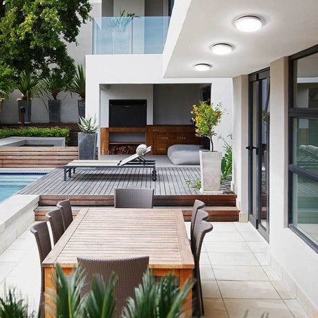 Plafonnier moderne LED Olly dans un espace extérieur élégant au-dessus d’une salle à manger et d’une piscine.