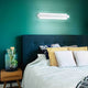 moderne LED Wandleuchte Regolo über einem Bett in modernem Schlafzimmer mit grüner Wand