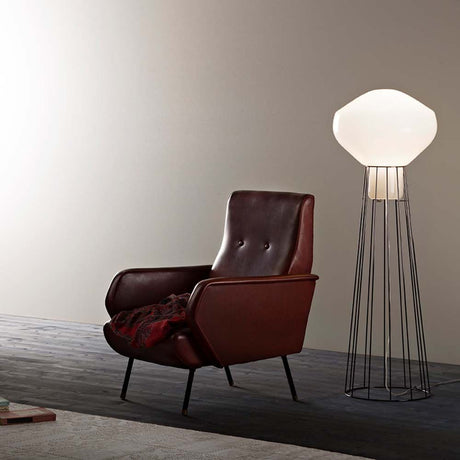 Fabbian Aérostat floor lamp Ø 43cm next to a stylish leather chair in a modern room