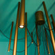 Fabbian Ari LED-Pendelleuchte 16-flammig mit goldenen Rohren und schwarzen Kabeln an blauer Wand.