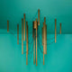 Fabbian Ari LED-Pendelleuchte 16-flammig in bronze mit schwarzem Kabel, designmodern auf türkisem Hintergrund.