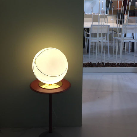 Fabbian Armilla table lamp gold on a table with a round shape and glossy glass diffuser.