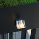 Fabbian Cubetto Wandstrahler GU10 an einer Wand montiert, mit transparentem Diffusor und dekorativem Lichteffekt.