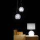 Fabbian Diamond&Swirl Pendelleuchte Diamond Ø 18cm über einem Tisch mit einer Tischlampe.
