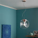 Fabbian Eyes Pendelleuchte Ø 35cm in modernem Wohnraum mit Kupferdetails und blauem Hintergrund