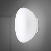 Applique Fabbian Lumi Poga avec verre soufflé à la bouche blanc sur fond gris.