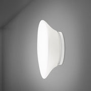 Fabbian Lumi Wandleuchte Mycena Small an einer grauen Wand montiert, mit elegantem Design und weißem Diffusor.