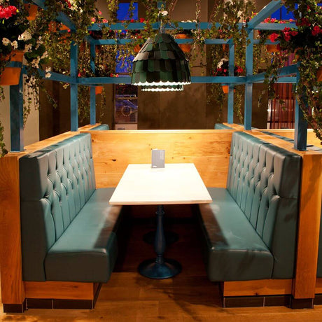 Gemütliche Sitzbank mit Tisch und Fabbian Roofer Hängeleuchte Steeple in einem modern gestalteten Restaurant.
