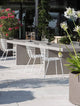 Moderne Terrassenmöbel mit weißen Stühlen, Pflanzgefäßen und blühenden Pflanzen im Freien.