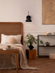 Fado Wandleuchte Ø 20,5cm E27 Rattan in modernem Schlafzimmer mit Bett und Pflanzen.