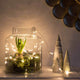 Feierliche LED Lichterkette IP20 dekoriert ein Glasgefäß mit Pflanzen und Lichtern in einem stilvollen Raum.